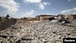 People look on, near the site of a building destroyed by a Saudi-led air strike near Sana'a, May 30, 2015. 