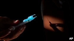 Un trabajador de la salud aplica una inyección de la vacuna contra el COVID-19 de Pfizer en un centro de salud comunitario en Brasilia, el 16 de enero de 2022.