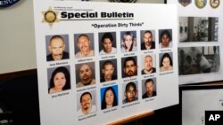 A poster showing photos of suspects, some of whom remain at large, at a news conference to announce indictments against the Mexican Mafia in Los Angeles, May 23, 2018.