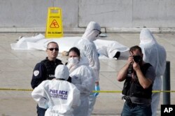 Police officers investigate by a body covered with white sheet outside Marseille's main train station, in Marseille, southern France, Oct. 1, 2017.