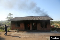 A man uses a cellphone to take pictures of a burning school office in Mashau Dolly village, in South Africa's Limpopo province, May 5, 2016.