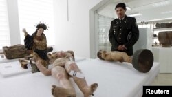 A police officer stands near art pieces during a news conference at Ecuador's National Cultural Heritage Institute (INPC) in Quito, Feb. 3, 2016. 