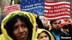 FILE - People hold signs before marching to Trump Tower in a protest organized by the New York Immigration Coalition against President-elect Donald Trump in New York, Dec. 18, 2016.