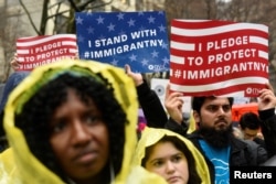 FILE - People hold signs before marching to Trump Tower in a protest organized by the New York Immigration Coalition against President-elect Donald Trump in New York, Dec. 18, 2016.