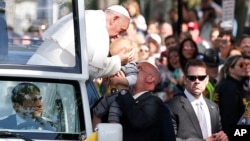 El papa Francisco besa a un bebé a su paso por una calle de Washington, en la Alameda Nacional.