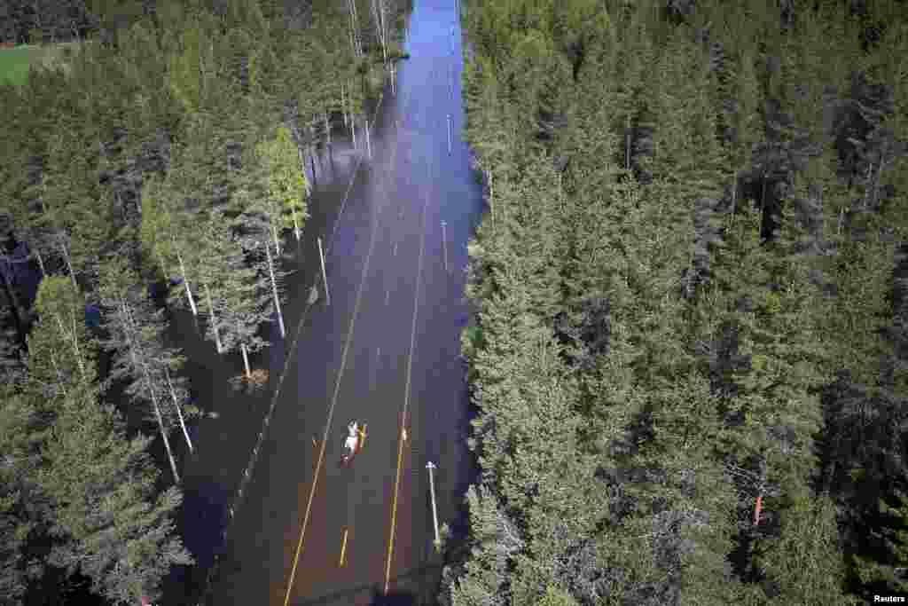 Two men paddle in a canoe on a flooded road in Trysil, southeast Norway. Rain and melted snow have increased the water level in the river Trysilelva.