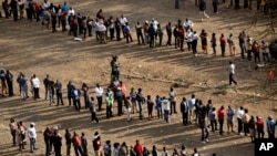 Kenyans queue to cast their votes at dusk at a polling station in downtown Nairobi, Aug. 8, 2017.