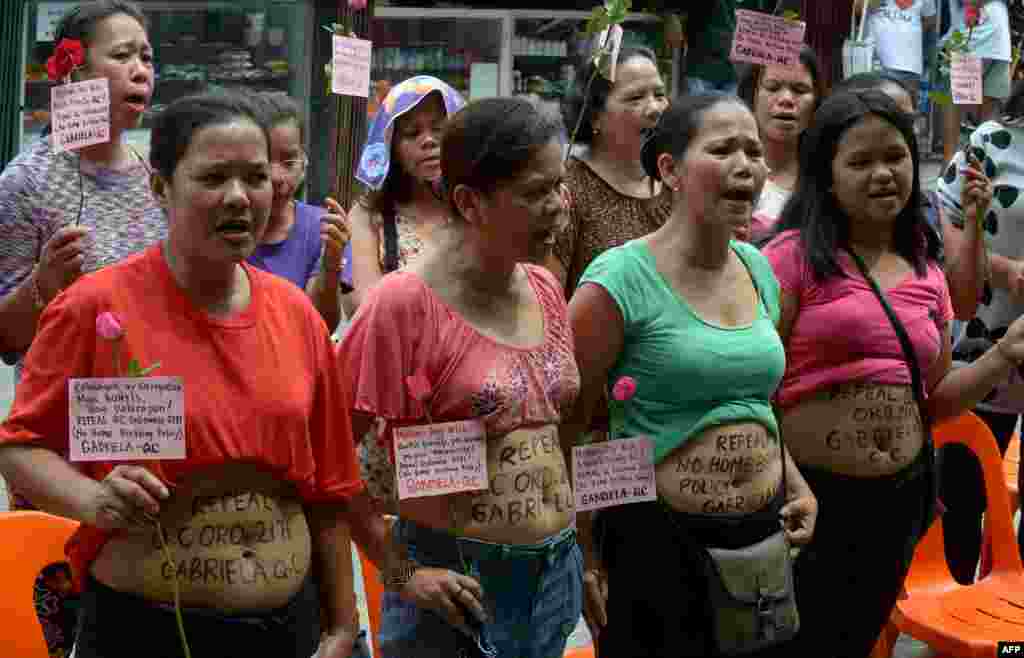 Para ibu menunjukkan perut mereka dan menyerukan pencabutan peraturan pelarangan melahirkan di rumah di pinggiran Manila, di Quezon City, Filipina. Para demonstran pada Hari Ibu memprotes kebijakan tersebut, yang berdampak terhadap para ibu miskin yang melahirkan dibantu oleh bidan informal atau ahli herbal dan mereka bisa dikenai denda sampai 5.000 peso.