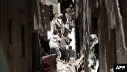 Yemenis sift through the rubble of a heavily damaged building following reported Saudi-led coalition airstrikes in the Yemeni capital Sanaa, May 16, 2019.