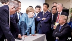  In this photo made available by the German Federal Government, German Chancellor Angela Merkel, center, speaks with U.S. President Donald Trump, seated at right, during the G7 Leaders Summit in La Malbaie, Quebec, Canada, on Saturday, June 9, 2018.