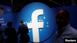 Para pengunjung berjalan melintas di depan logo Facebook dalam konferensi para pengembang di San Jose, California, 30 April 2019. 
