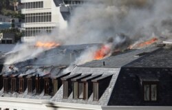 Flames and smoke rise over a roof of the parliament as the fire flared up again, in Cape Town, South Africa, Jan. 3, 2022.