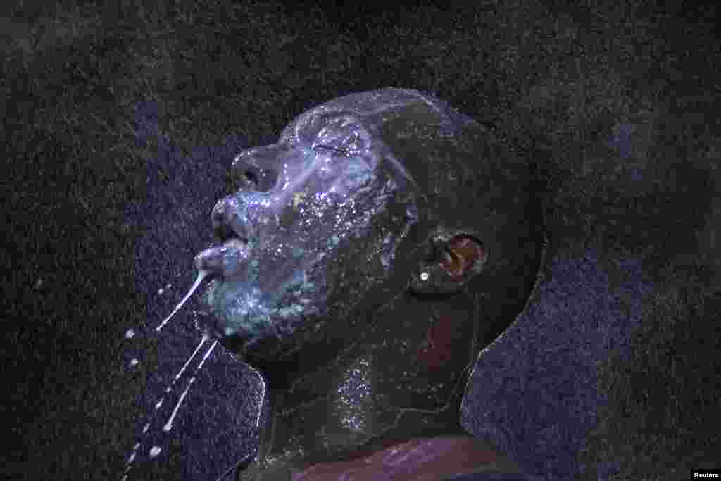 Seorang pria membasuh wajahnya dengan susu dan air setelah matanya sakit akibat gas airmata yang disemprotkan oleh pasukan keamanan di Ferguson, Missouri (20/8). (Reuters/Adrees Latif)