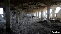 A Palestinian worker walks inside al-Awdah food factory, which witnesses said was shelled and torched by the Israeli army during the offensive, in Deirl al-Balah, central Gaza Strip, Aug. 14, 2014. 