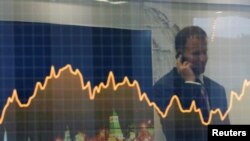 FILE - A participant is reflected in a display showing business and financial information at the VTB Capital "Russia Calling!" Investment Forum in Moscow, Russia, Oct. 2, 2014.