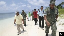 Armed Forces of the Philippines Western Command commander Lt. Gen. Juancho Sabban, right, Kalayaan municipality Mayor Eugenio Bito-onon, 2nd right, and Philippine Congressman Walden Bello, 3rd right, walk along the shores of Pagasa Island, part of the dis