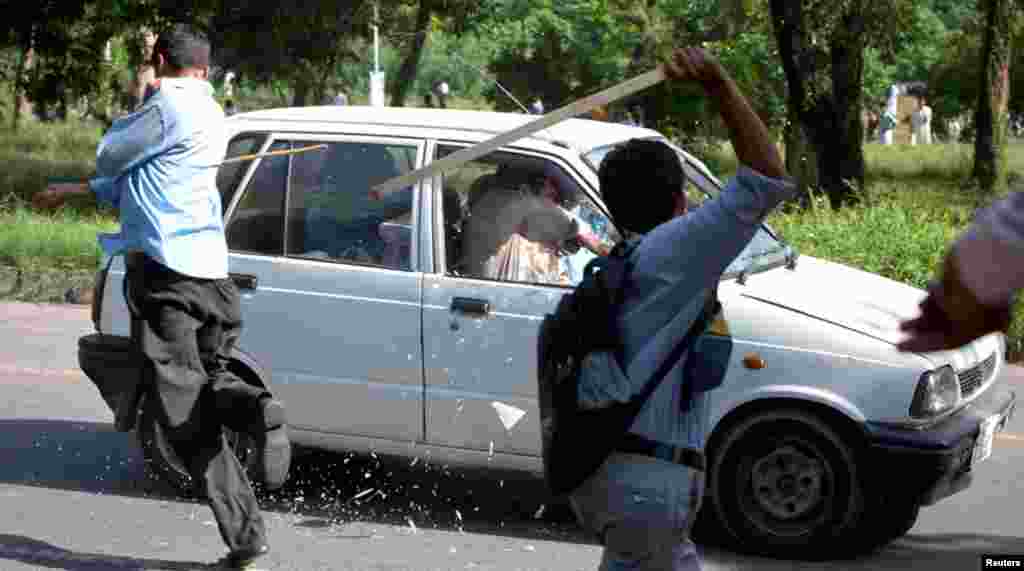 Protesters use sticks to smash the windscreen and windows of a car during an anti-America protest march in Islamabad September 20, 2012.