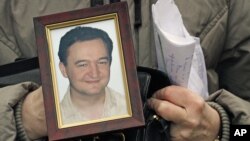 A November 2009 photo shows a portrait of lawyer Sergei Magnitsky who died in jail, held by his mother Nataliya Magnitskaya in Moscow. 