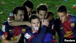 Barcelona's Lionel Messi, with a dummy in his mouth, carries his son Thiago near his team mates during the Spanish league first division trophy celebrations at Camp Nou stadium in Barcelona May 19, 2013. Barcelona moved a step closer to matching Real Madr