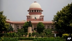 FILE - A gardener works on the lawns of the Supreme Court in New Delhi, India, Aug. 22, 2017.