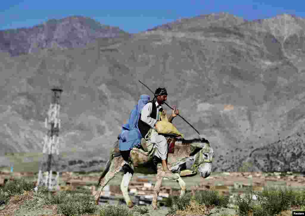 A family rides on a donkey as they travel along a road on the outskirts of Parwan province, Afghanistan.