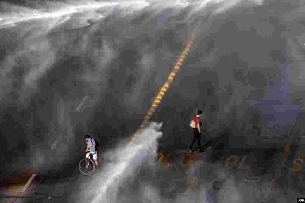 Demonstrators are sprayed by a riot police water cannon during clashes following a protest against Chilean President Sebastian Pinera's government in Santiago, Nov. 18, 2020.