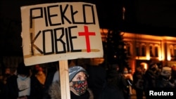 A demonstrator holds a placard reading "Women's hell" as she protests against a verdict restricting abortion rights in Warsaw, Poland, Jan. 27, 2021. 