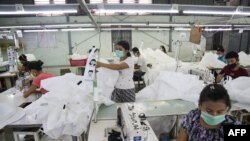 This photo taken on May 8, 2020 shows workers wearing face masks sewing disposable surgical gowns for health workers as protection from the COVID-19 coronavirus at a garment factory in Yangon. - The factory which has switched from making clothes for expor