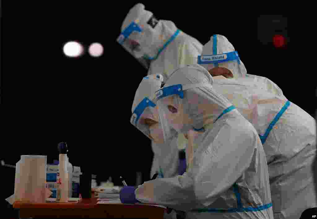 Medical staffers wearing protective suits work at a triage checkpoint that was set up to ease the pressure on hospital emergency wards, following the surge of COVID-19 cases, in Milan, Italy.