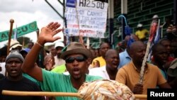 FILE - A miner gestures as they gather at Wonderkop stadium outside the Lonmin mine in Rustenburg, northwest of Johannesburg, Jan. 30, 2014.