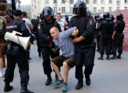 Police officers detain a man during an unsanctioned rally in the center of Moscow, Russia, July 27, 2019.