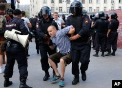 Police officers detain a man during an unsanctioned rally in the center of Moscow, Russia, July 27, 2019.