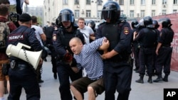 Seorang polisi menahan seorang pria dalam ikut unjuk rasa tanpa izin di pusat Kota Moskow, Rusia, Sabtu, 27 Juli 2019. 