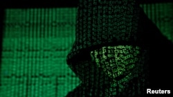 (FILE) A Projection of cyber code on hooded man is pictured in this illustration picture.