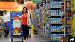 FILE - In this Nov. 9, 2017, photo, Laila Ummelaila, a personal shopper at the Walmart store in Old Bridge, N.J., pulls a cart with bins as she shops for online shoppers. 