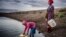 FILE: Martha Kasafi (right) and her daughter, both refugees from Democratic Republic of Congo, collect water for their vegetable crops at a water pan in Kalobeyei settlement for refugees in Turkana County, Kenya on Oct. 2, 2019.