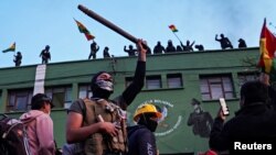 Opponents to Bolivia's President Evo Morales react as police officers stand on the roof of their headquarters, in Cochabamba, Bolivia, Nov. 8, 2019. 
