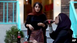 An Iranian drinks a Coca-Cola and smokes a Marlboro cigarette at a cafe in downtown Tehran, Iran, Wednesday, July 10, 2019. 