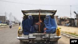 FILE - Afghan women and a boy travel in a taxi car on the outskirts of Mazar-i-Sharif, May 13, 2020.