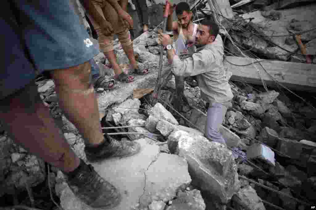 Palestinians search the rubble of a destroyed house where five members of the Ghannam family were killed in an Israeli missile strike in Rafah refugee camp, southern Gaza Strip, July 11, 2014. 