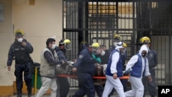 Inmates wearing white protective suits, and security agents, transport an inmate to a clinic at the Lurigancho prison on the outskirts of Lima, Peru, Aug. 19, 2020. 