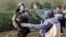 FILE - A Macedonian police officer hits a stranded migrant attempting to cross the Greek-Macedonian border, near Gevgelija, Macedonia, Dec. 2, 2015. 