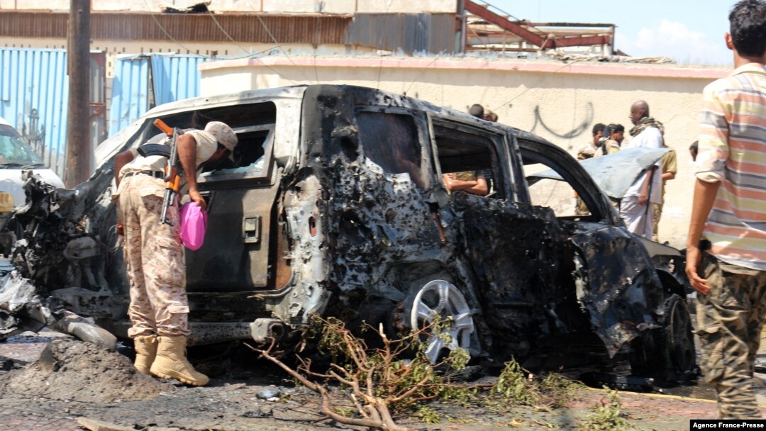 Yemeni security forces and rescue teams gather around the carcass of a burnt car following an explosion that hit Yemen's southern port city of Aden, Oct. 10, 2021.