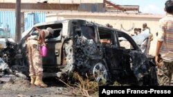 Yemeni security forces and rescue teams gather around the carcass of a burnt car following an explosion that hit Yemen's southern port city of Aden, Oct. 10, 2021.