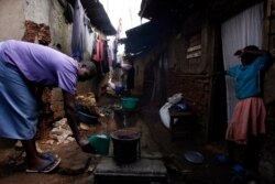 FILE - A woman lights a charcoal stove in an alley in Nairobi's Kibera slum, Feb. 6, 2008.