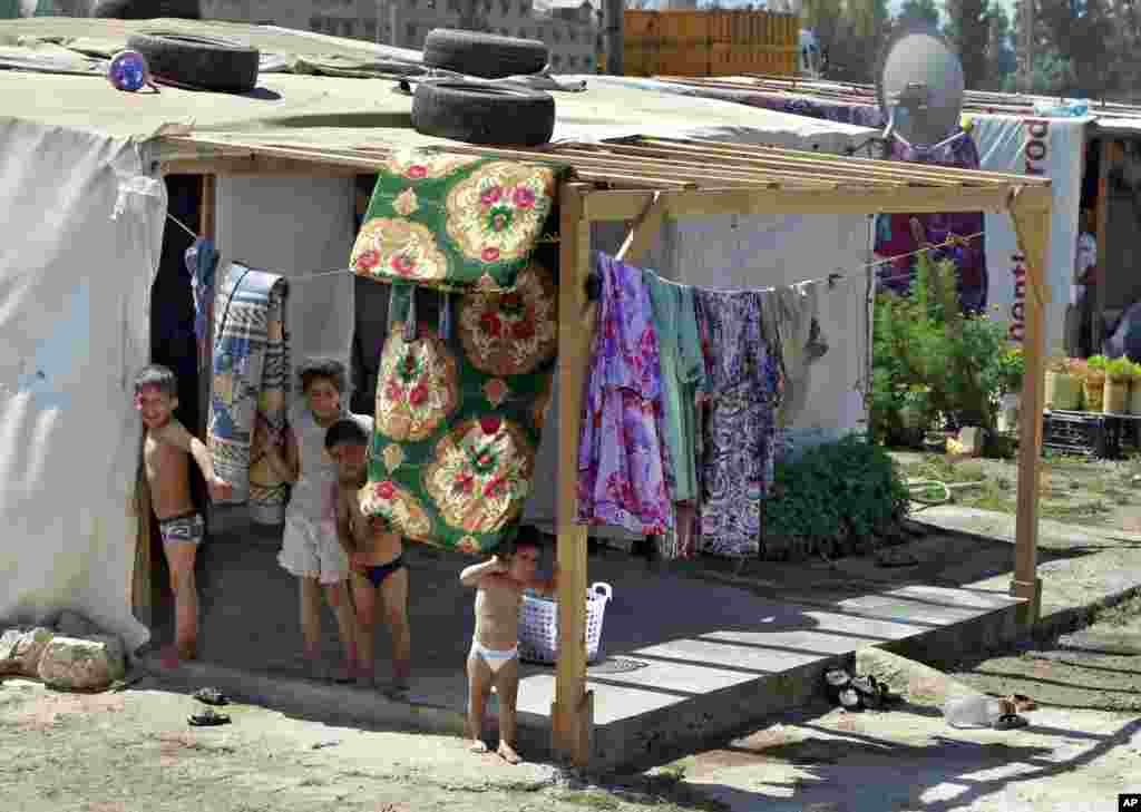 Syrian refugee children stand outside their tent, at a temporary refugee camp in the eastern Lebanese town of Faour near the border with Syria, August 28, 2013. 