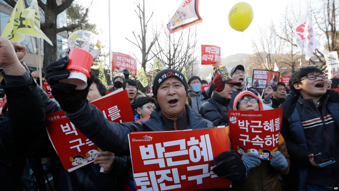 Para pemrotes membawa spanduk bertuliskan "Tahan Park Geun-hye" sambil meneriakkan slogan saat berpawai menuju kantor Presiden di Seoul, 10 Desember 2016 (AP Photo/Ahn Young-joon).