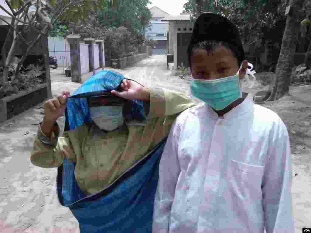 Dua orang siswa memakai masker untuk melindungi diri dari hujan abu di Sleman, Yogyakarta. (VOA/Nurhadi Sucahyo)