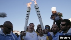 Le président du Comité olympique passe la flame au réfugié syrien Ibrahim Al-Hussein à Athènes, le 26 avril 2016.