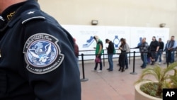 FILE - Pedestrians crossing from Mexico into the United States at the Otay Mesa Port of Entry wait in line in San Diego.